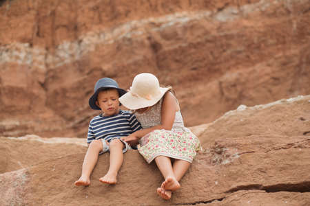Two kids hugging sitting in the mountain. Big sister and brotherの写真素材