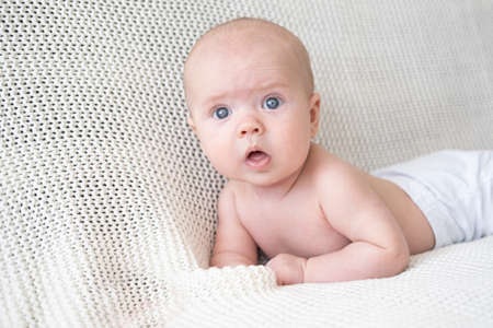 exicited little baby boy lying on white plaid. Happy family