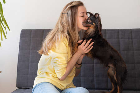 Happy blonde woman kiss embrace funny brown russian toy terrier