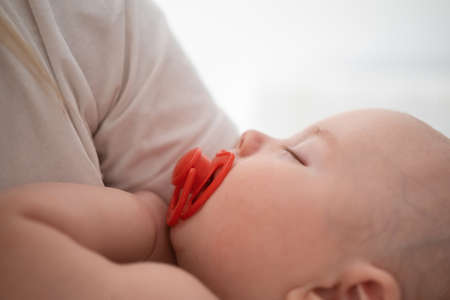 little sleeping baby boys face in mother hands. maternity concept. nippleの写真素材