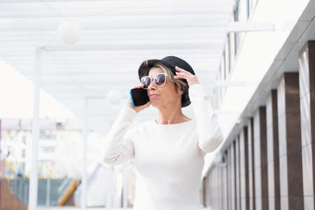 Fashion business senior attractive woman walking with phone in the city
