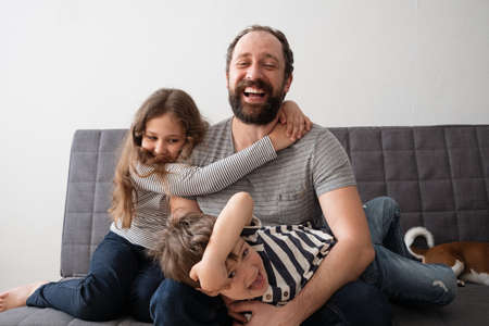 little caucasian girl and boy hug father