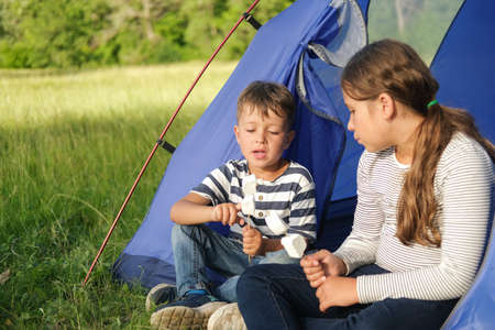 Two kids sit and eat marshmallow in tentの写真素材
