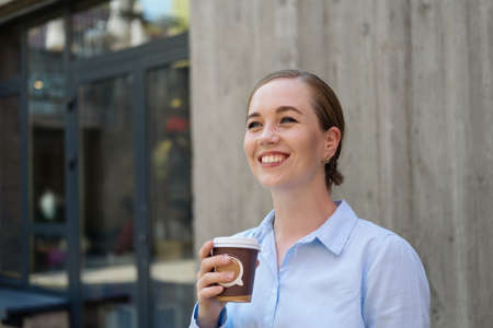 happy confident business woman drinking coffee stand in cityの写真素材