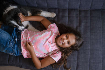 Playful happy Australian shepherd dog lying play with owner girlの写真素材