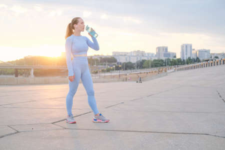 Young fitness woman finish running in the city, drinkの写真素材