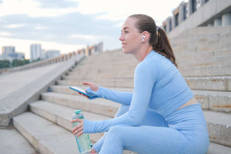 Young fitness woman finish running, sit and relaxの写真素材