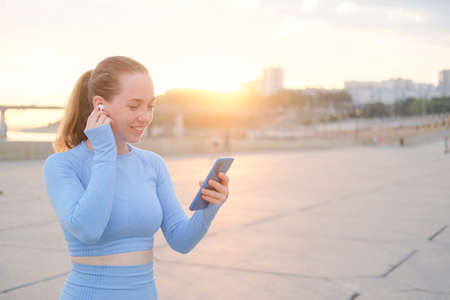 Young fitness woman start running, choose music in phoneの写真素材