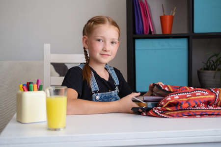 Cute redhead girl packing backpack, preparing for schoolの写真素材