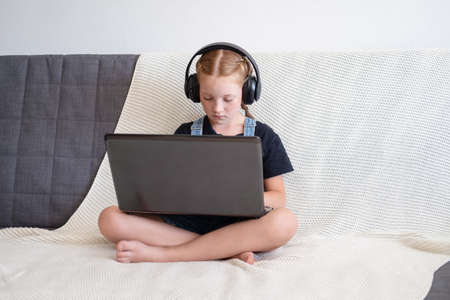 caucasian redhead girl in headphones using laptop studying at homeの写真素材