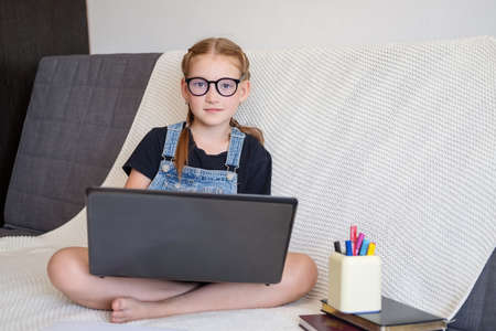 caucasian happy redhead girl in eyeglasses using laptop studying at homeの写真素材