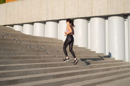 Young fitness woman run on stairs, listen musicの写真素材
