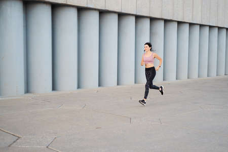 Young fitness woman run in city, listen musicの写真素材