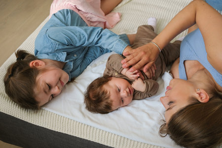 Attractive happy mother lying with two daugther. little baby girl. Happy familyの写真素材