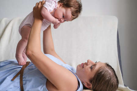 Attractive happy mothers hold, play with little baby girl. Happy familyの写真素材
