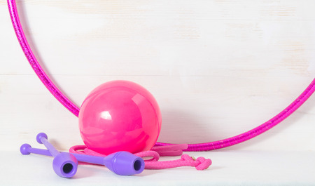 gymnastic equipment. Skipping rope, clubs for rhythmic gymnastics, hoop and ball on white wooden...