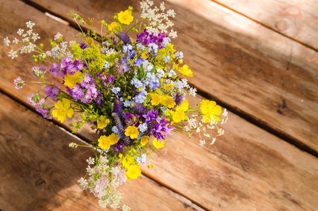 beautiful bouquet of bright wildflowers on a wooden table backgroundの写真素材