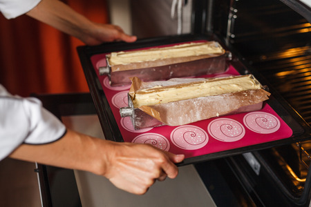 Woman cooking in the kitchen, puts cakes in the ovenの写真素材