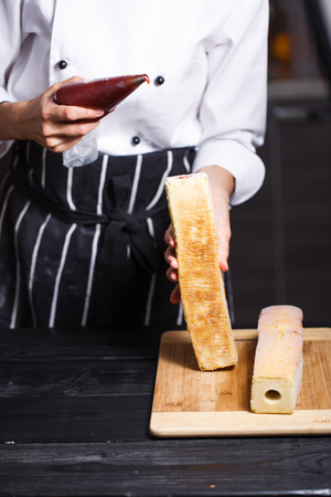 female hands holding piping bag filled with cream frosting cakeの写真素材