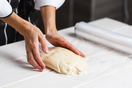 kneading by women hands on white wooden table