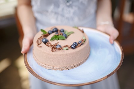 Baker hands holding delicious creamy cake closeupの写真素材