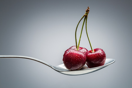 cherry on curved spoon with reflection on gradient backgroundの写真素材