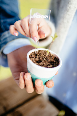 Beautiful young couple in casual clothes is holding a plant. Cyrillic names on tabletsの写真素材