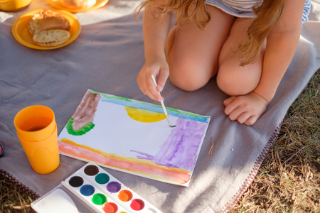 Closeup of sweet little girl drawing in the park on the blanketの写真素材