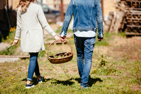 young couple carries a basket with seedlings in casual clothesの写真素材