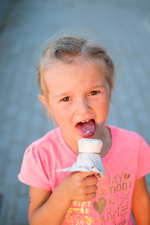 Girl in pink t-shirt licks ice creamの写真素材