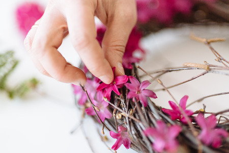 Girl florist makes a bouquet in the form of a nest on a white tableの写真素材