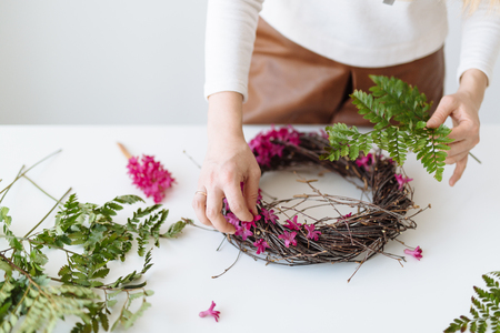 Girl florist makes a bouquet in the form of a nest on a white tableの写真素材