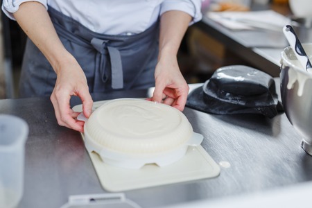 Woman in white uniform prepares food in a professional kitchenの写真素材