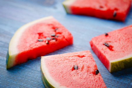 Slices of ripe watermelon on a blue wooden countertopの写真素材