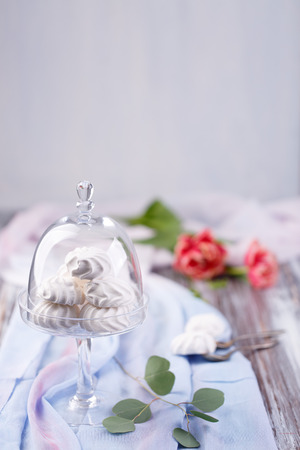 marshmallows in a glass stand on a blue fabric. red roses in the background. light backgroundの写真素材