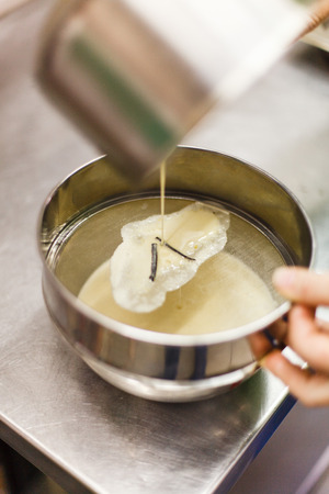 the process of straining when preparing the brule cream. vanilla pods on a steel sieve. professional kitchen.の写真素材