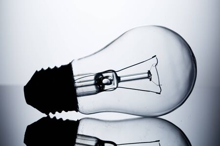 Incandescent lamp lying on a table on a gray gradient background with reflection