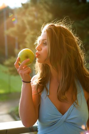 Girl with apple on sunsetの写真素材