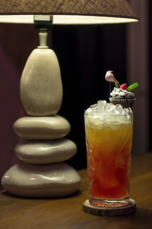 Cold cocktail with grapefruit and a cupcake decorated with a birdの写真素材