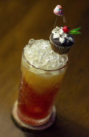 Cold cocktail with grapefruit and a cupcake decorated with a birdの写真素材