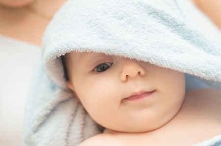 Portrait of a little girl, a child in a blue towel. At the hands of my mother.の写真素材
