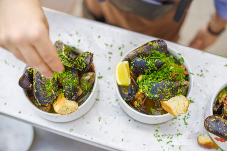 A portion of cooked mussels on a plate. Outdoor food on the terrace. Close-up plate of mussels.の写真素材