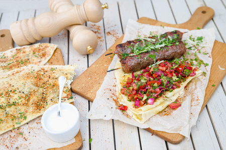 Kebab and Gozleme .Traditional oriental meat kebab of minced beef or lamb with vegetables and herbs overhead marble cutting boar. Gozleme with herb and cheese. Food on a wooden table.の写真素材