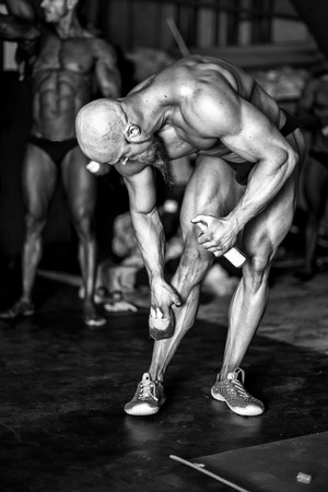 Bodybuilding competition backstage: contestant being oiled and fake tan applied to skin. selective focus. black and white photography.の写真素材
