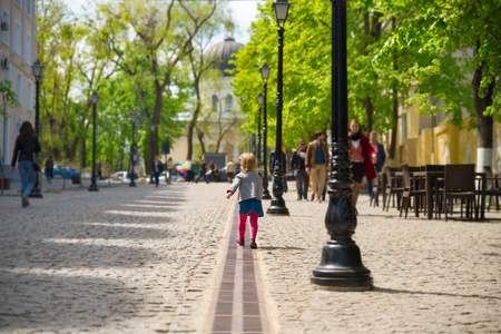Little girl walking along the street, paving stonesの写真素材