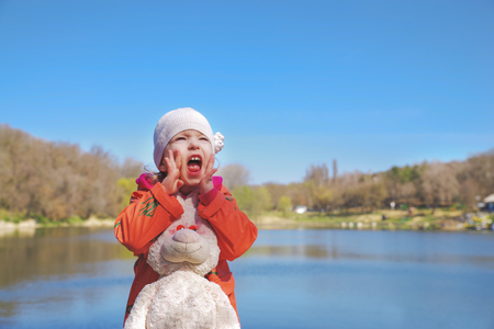 Closeup portrait of a screaming girl, in the park on the background of the lakeの写真素材