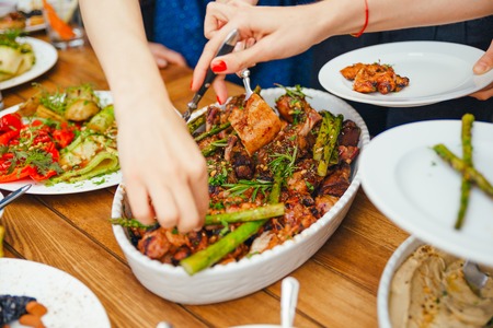 Women's hands pile themselves a meal in a plate of lunch. The concept of nutrition. Buffet. Food. Dinner. The concept of sharing. close-upの写真素材