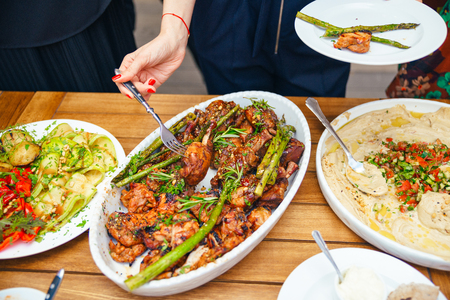 Women's hands pile themselves a meal in a plate of lunch. The concept of nutrition. Buffet. Food. Dinner. The concept of sharing. close-upの写真素材