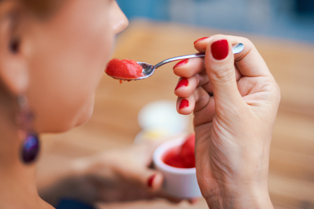 Closeup of a woman's hand holding a cup with homemade red ice cream. Breakfast, snacks. The concept of healthy eating and lifestyle.の写真素材
