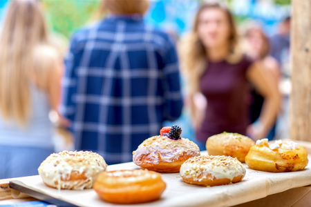 Close-up of delicious baked donuts with glazing and berries in sunlight. Bokeh, in the background people in the defocusの写真素材